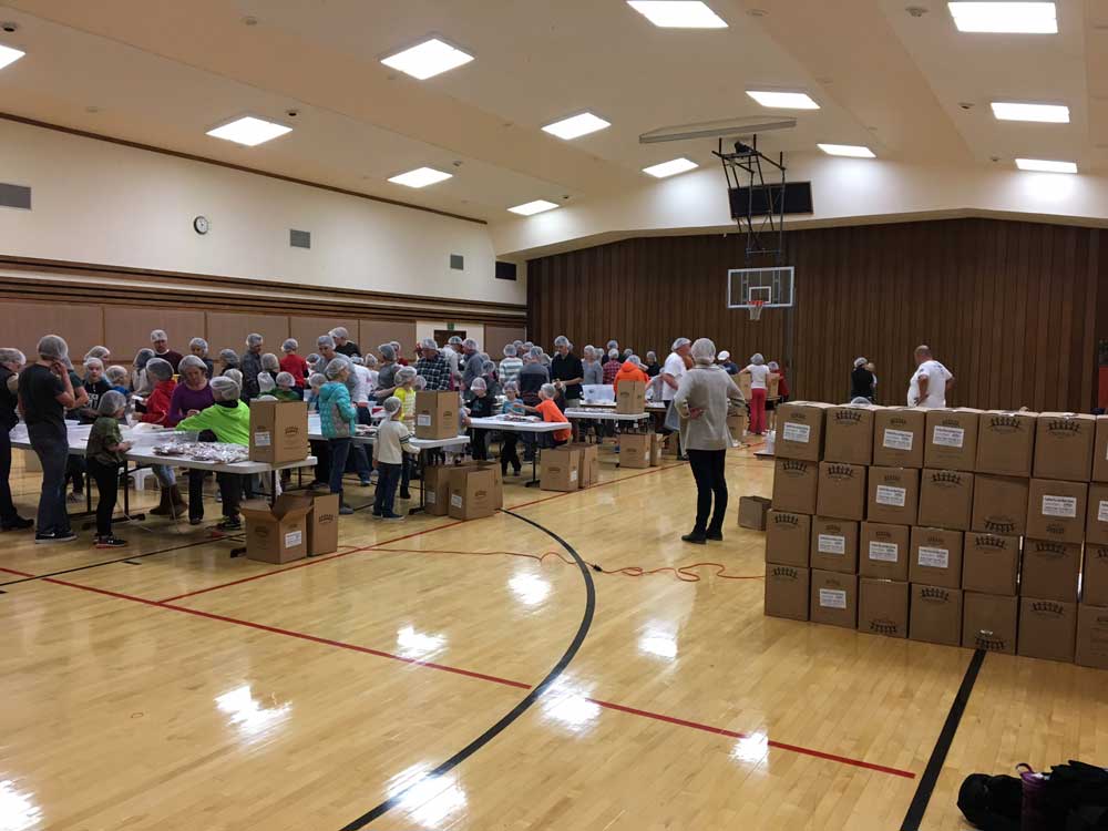 Volunteers in a gymnasium packing meals