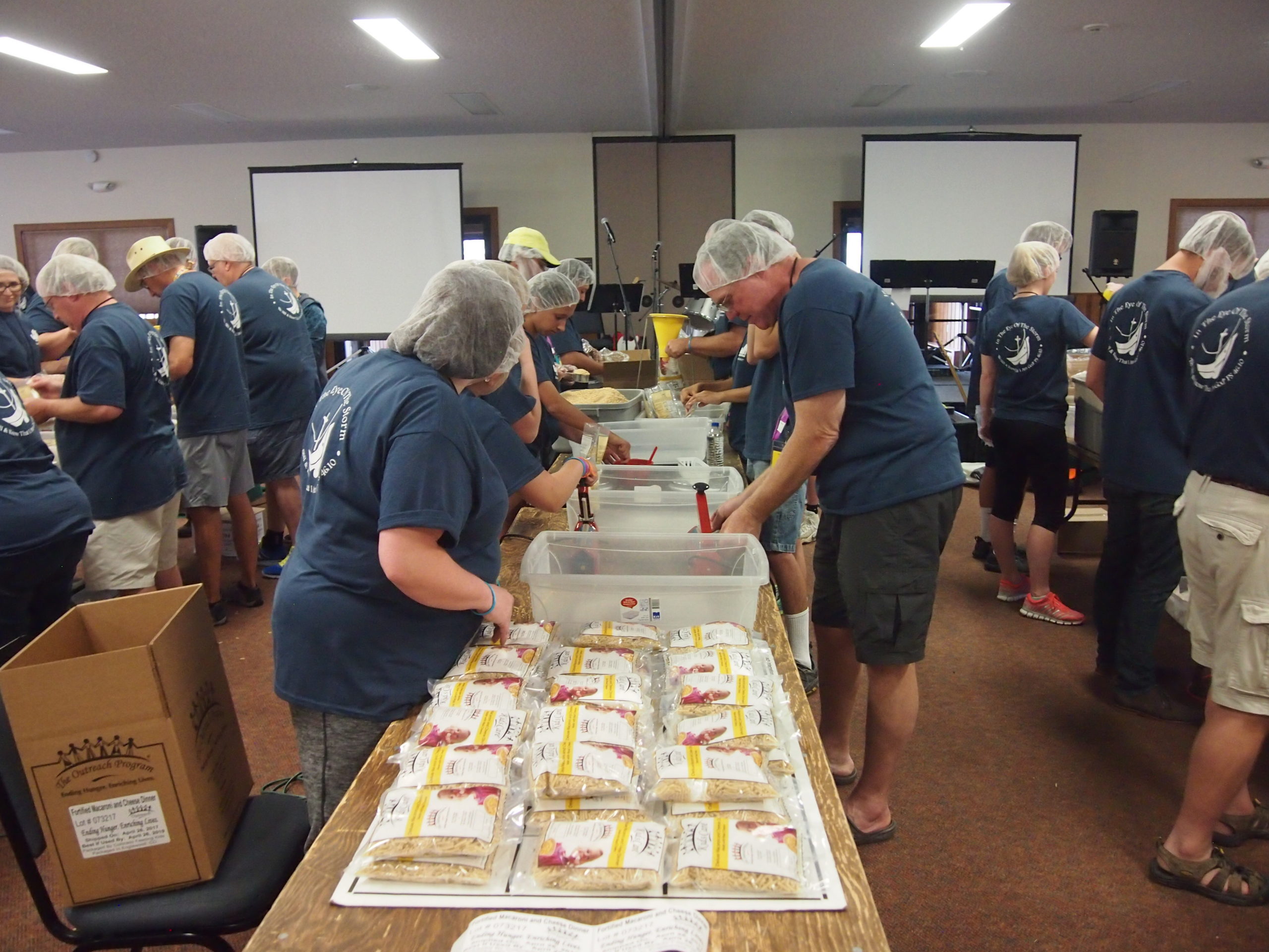 A group of volunteers packing meals and wearing hair nets