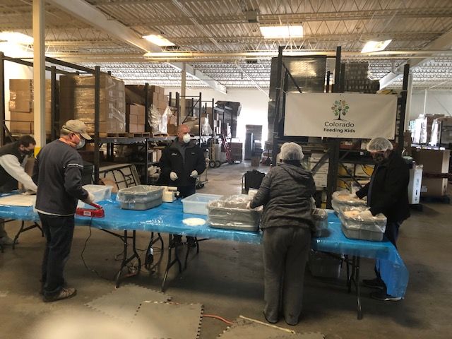 A group of volunteers packing meals and wearing hair nets and masks